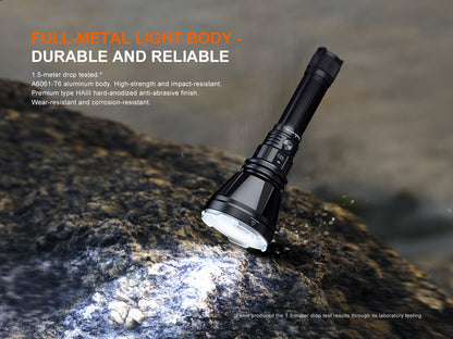 Black Fenix HT18R V2.0 Flashlight on a rock with water in the background, highlighting durability.