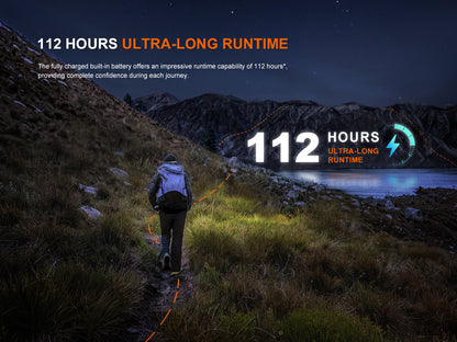 Person hiking at night using Fenix HL12R V2.0 Headlamp with scenic mountain view, highlighting 112-hour ultra-long runtime feature.