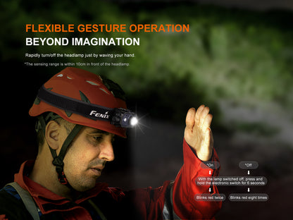 Person wearing a red helmet with a Fenix HL45R Headlamp, demonstrating gesture control in a dark setting.