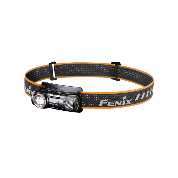 A black Fenix HM50R headlamp with an orange adjustment strap, featuring a white LED light and the Fenix brand name on the strap.